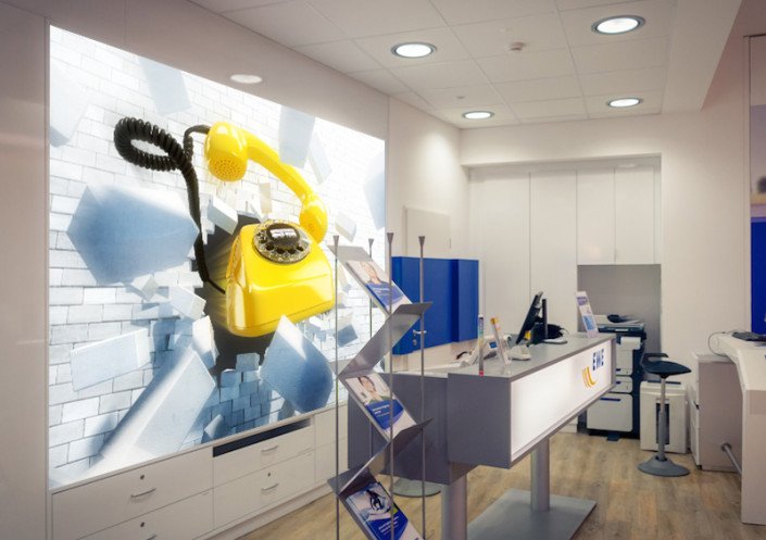 Frese & Wolff Werbeagentur, Keyvisual für die EWE Festnetz-Kampagne in einem EWE Store, zu sehen ist ein gelbes Telefon, das eine Mauer durchbricht